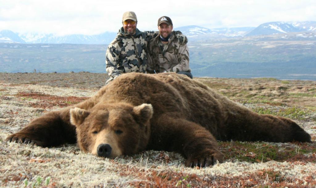 Охотники возле огромного медведя.